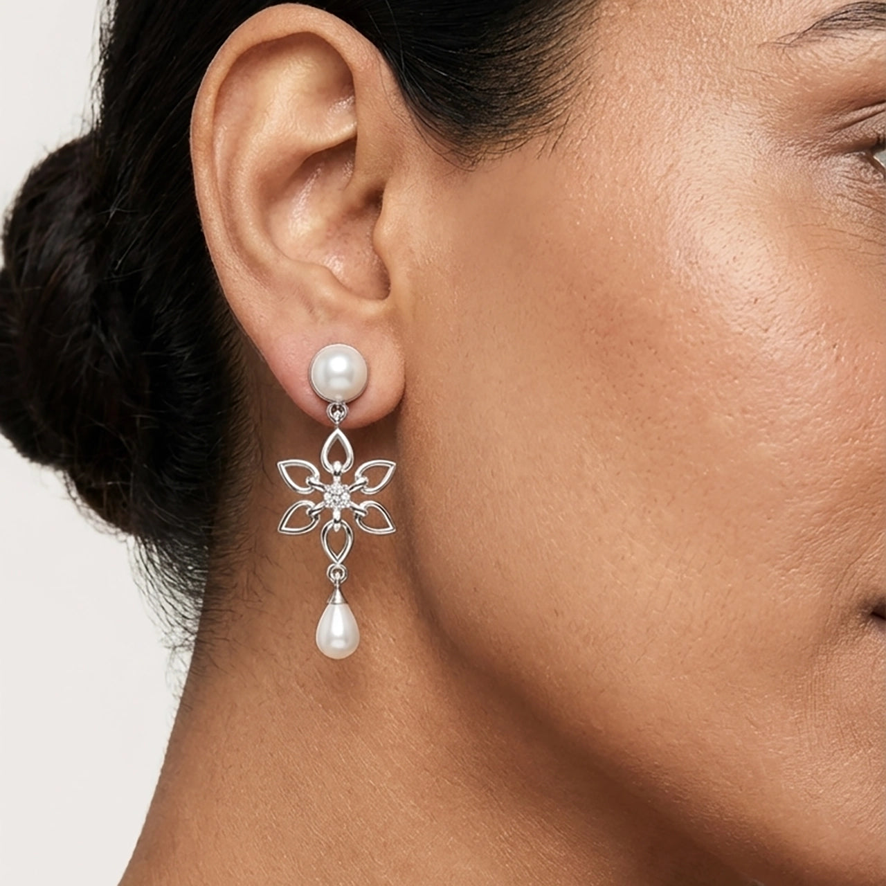 Close-up of a woman wearing a silver earring with a pearl drop by Sohvii