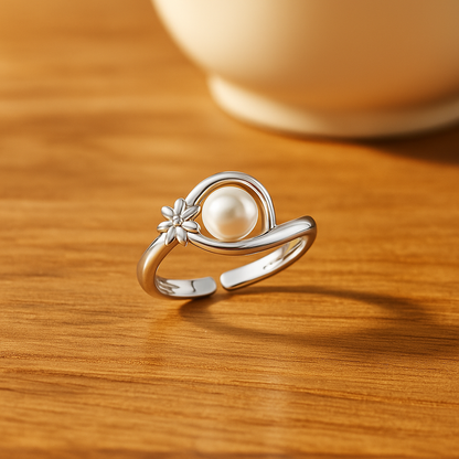92.5 Silver ring with a freshwater pearl and small flower design on a wooden surface
